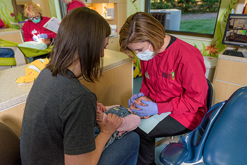 picture of Dr. Lindsay and a client checking the client's baby's teeth.