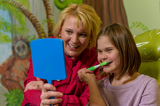 A picture of Dr. Coffield and a child going over good teeth brushing with a mirror